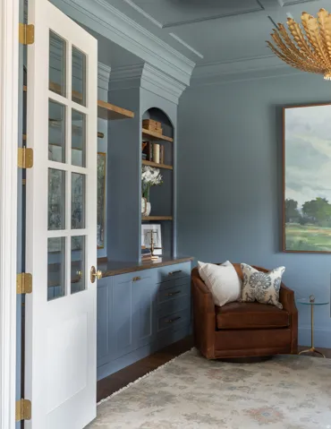 Built-in cabinetry with wood-finish countertop, arched shelving, and paneling