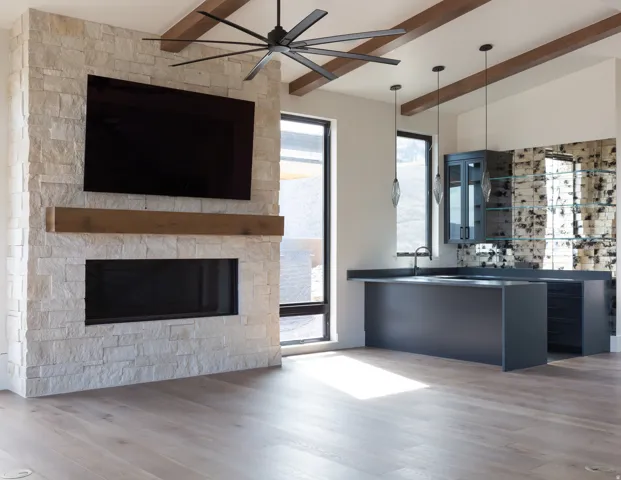 Stone-clad fireplace with a recessed linear firebox, wood-finish mantel, and built-in media space