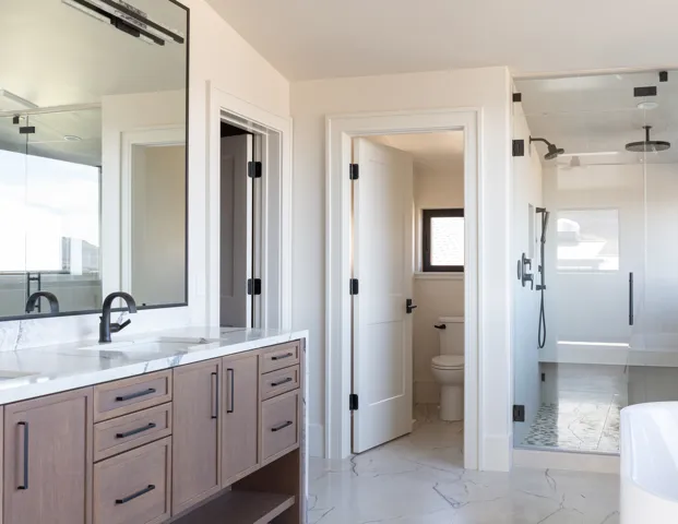 Dual vanity with stone countertop, matte black fixtures, and wood-finish cabinetry