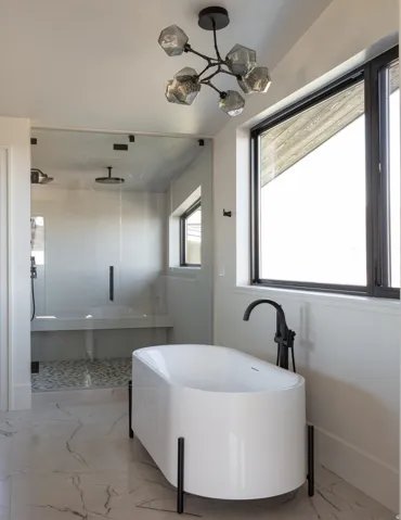 Freestanding soaking tub with floor-mounted fixture, walk-in shower with bench seating, tiled shower floor, and contemporary overhead lighting