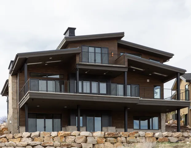 Multi-level exterior featuring wood-finish siding, stone accents, multiple covered balconies, and extensive glass doors