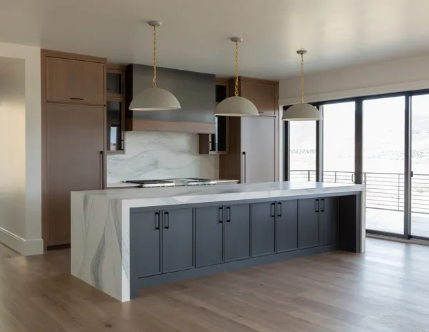 Waterfall island with integrated cabinetry, wood-finish flooring, full-height decorative backsplash, built-in range, and sliding glass doors