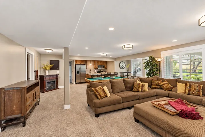 Expansive carpeted room featuring recessed lighting, a built-in fireplace, and large windows with plantation shutters