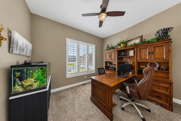 Vaulted ceiling, ceiling fan with integrated lighting, window with plantation shutters, built-in wooden cabinetry, and plush carpeting