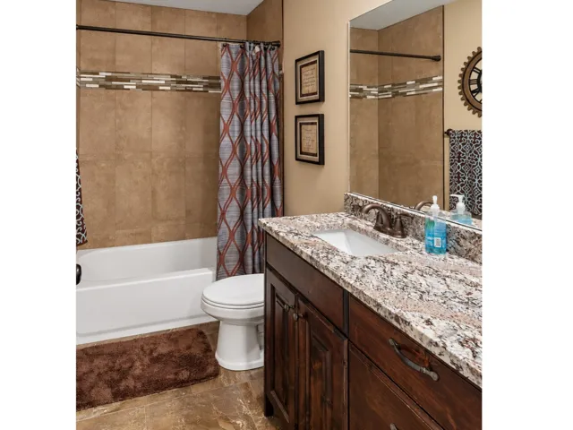 Vanity with a granite countertop, undermount sink, and dark wood cabinetry