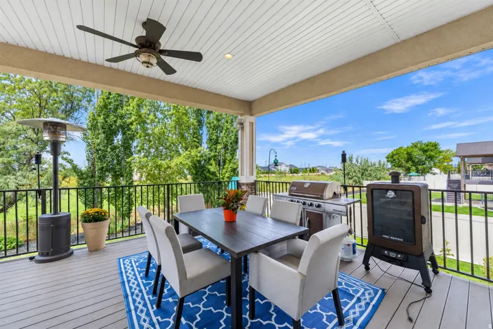 Covered porch with a ceiling fan, recessed lighting, composite decking, and black metal railings