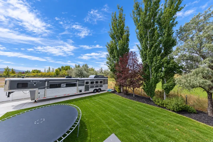 Manicured lawn, mature trees, and landscaping with dark ground cover