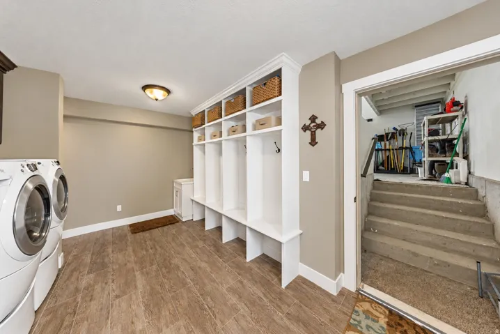 Laundry area with wood-finish flooring, built-in storage cubbies, and overhead shelving