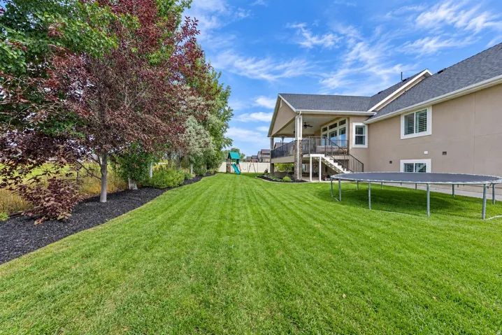 Expansive lawn featuring mature trees and a mulched border