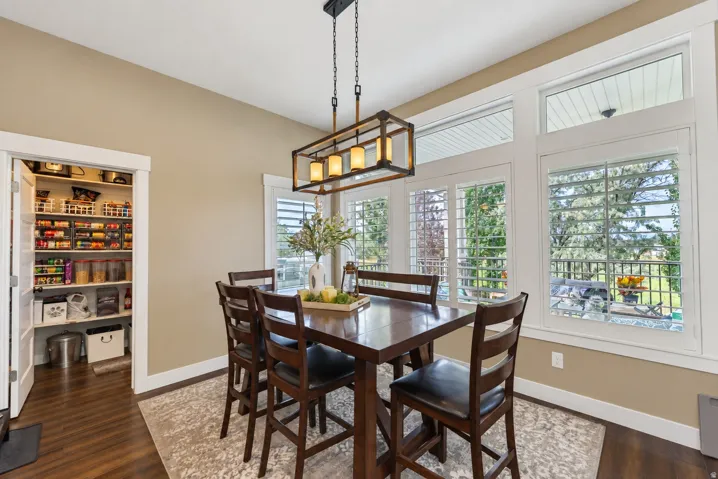 Dining area featuring wood-finish flooring, a contemporary chandelier, plantation shutters, and a walk-in pantry with built-in shelving