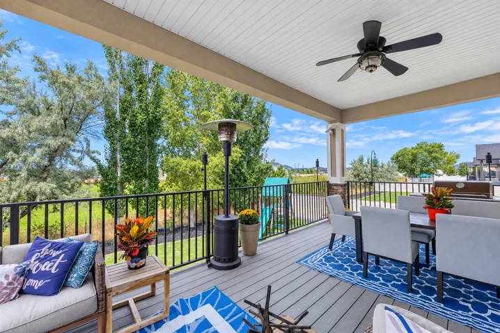Covered patio featuring a ceiling fan, composite decking, and black metal railing