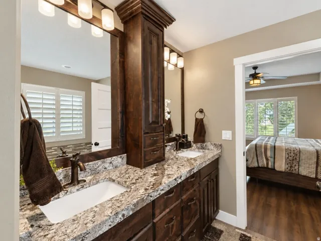 Dual vanity with granite countertop, shaker-style cabinetry, and oil-rubbed bronze fixtures