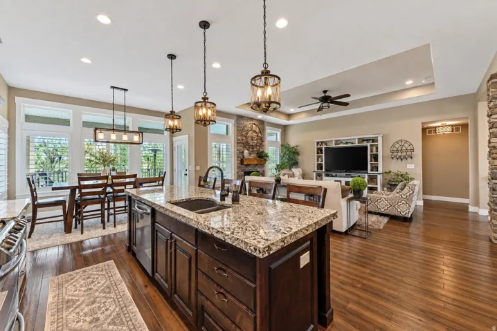 Gourmet kitchen island with granite countertops, integrated sink, and dark wood cabinetry