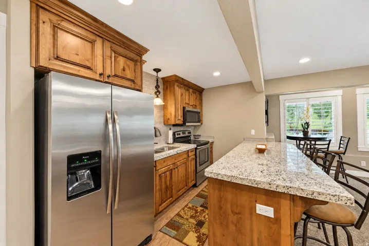 Kitchen featuring wood cabinetry, stainless steel appliances, granite countertops, a tiled backsplash, and recessed lighting