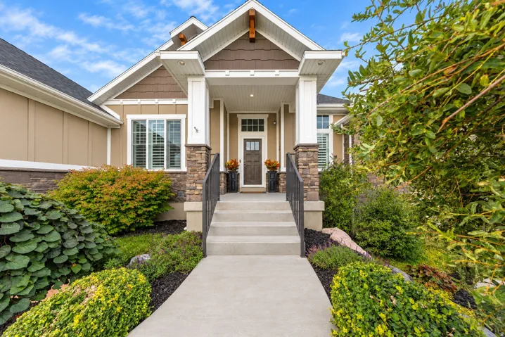 Crafted exterior featuring a covered entry, stone column accents, and a dark-paneled front door