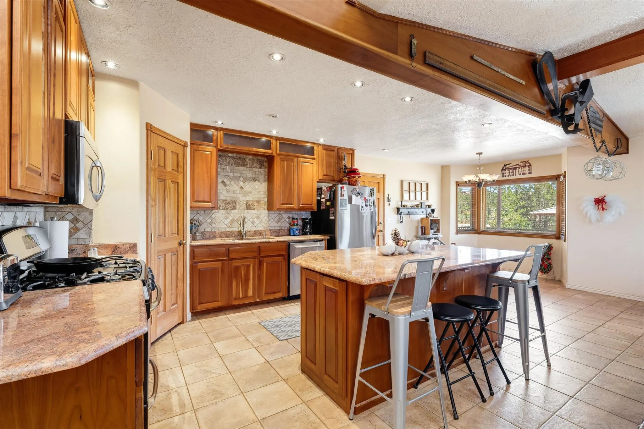 Spacious kitchen featuring a large central island, wood cabinetry, tile flooring, and recessed lighting