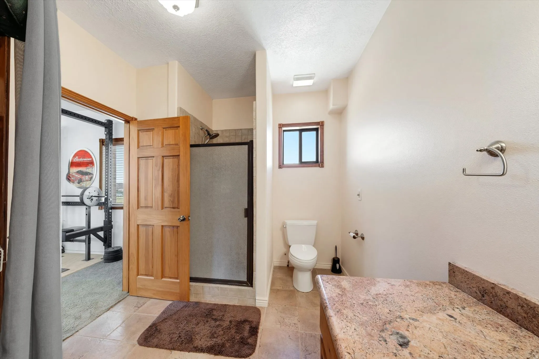 Bathroom with a single vanity featuring a stone countertop, a toilet, a shower with a framed glass enclosure, and a wood-framed window