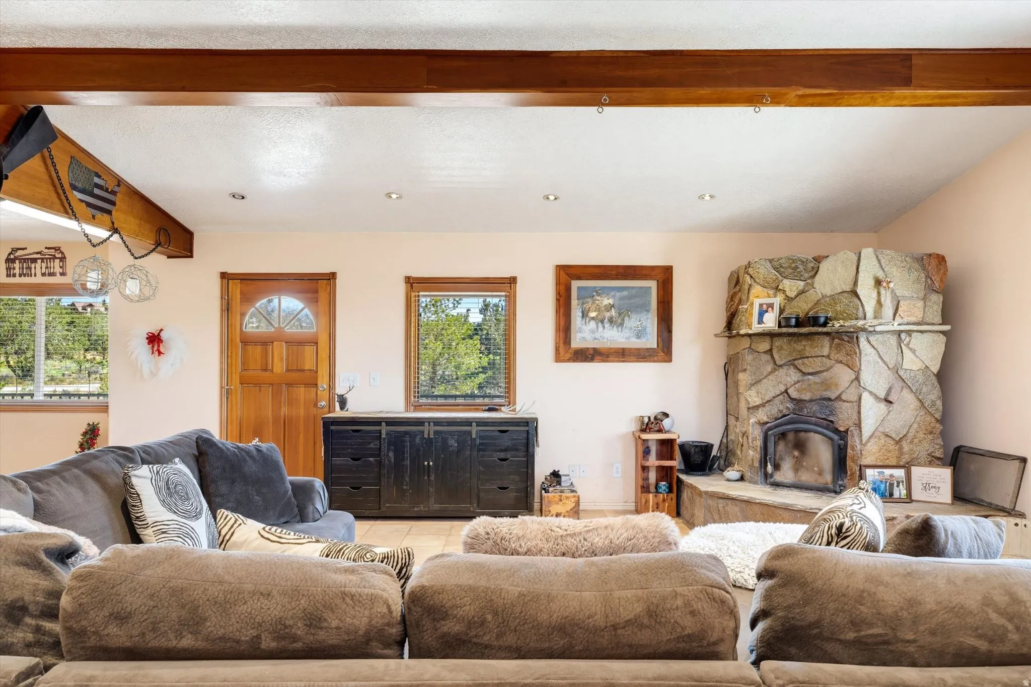 Stone-clad corner fireplace with a raised hearth, wood-paneled ceiling beams, recessed lighting, and tiled flooring