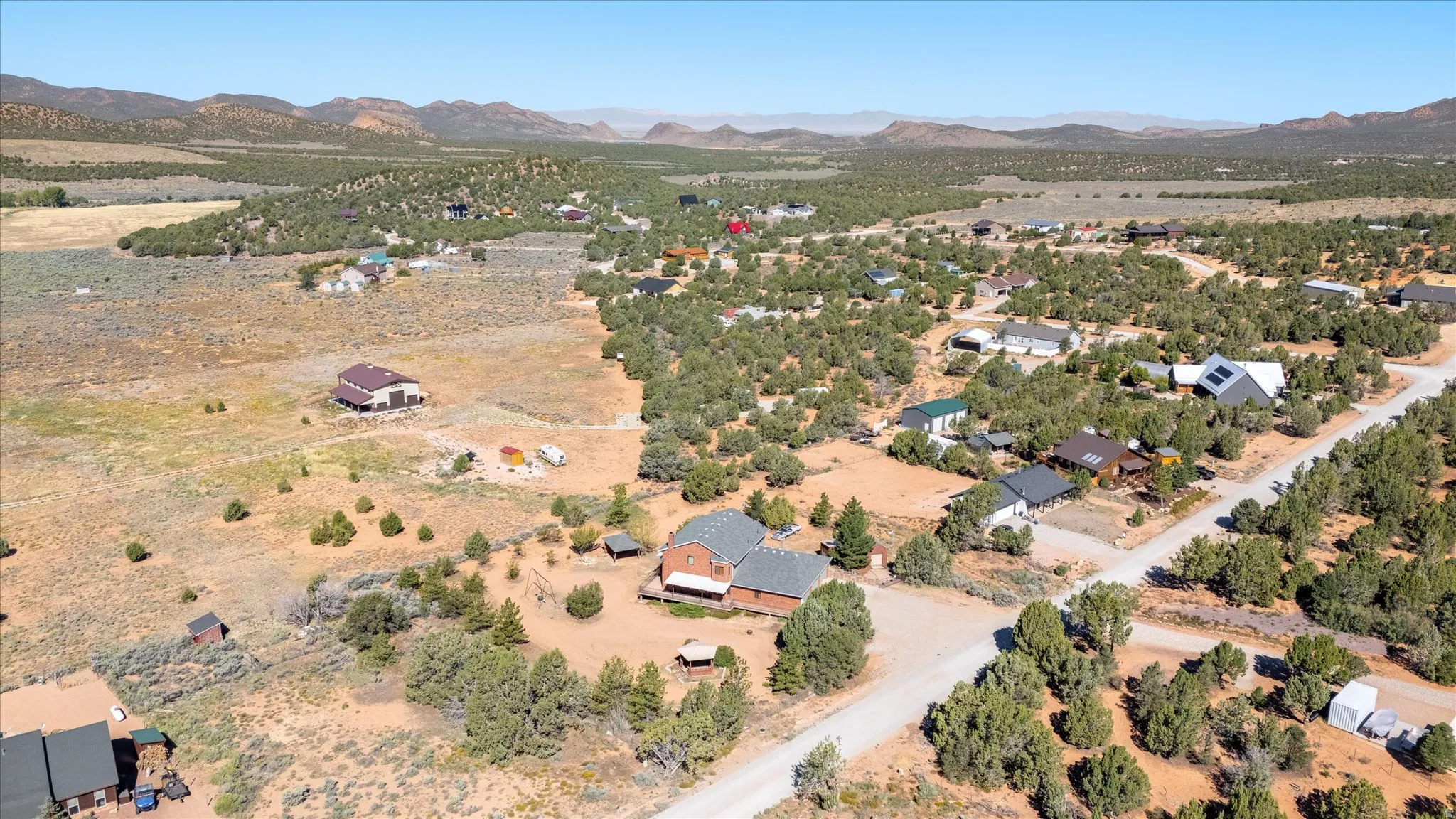 Expansive landscape featuring scattered residential properties, mature trees, and mountainous terrain