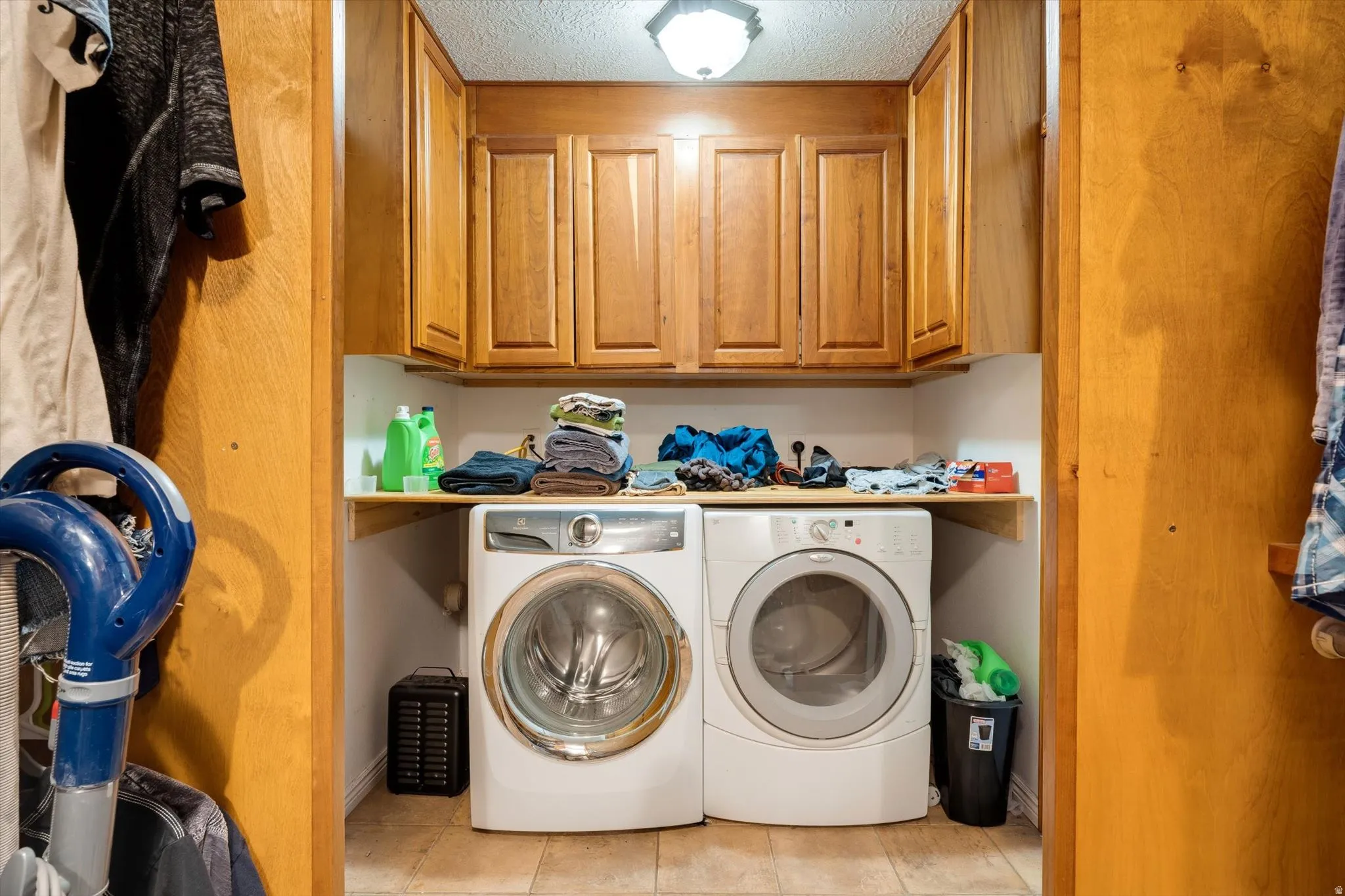 Laundry area featuring wood-finish cabinetry, a built-in shelf, and tile flooring