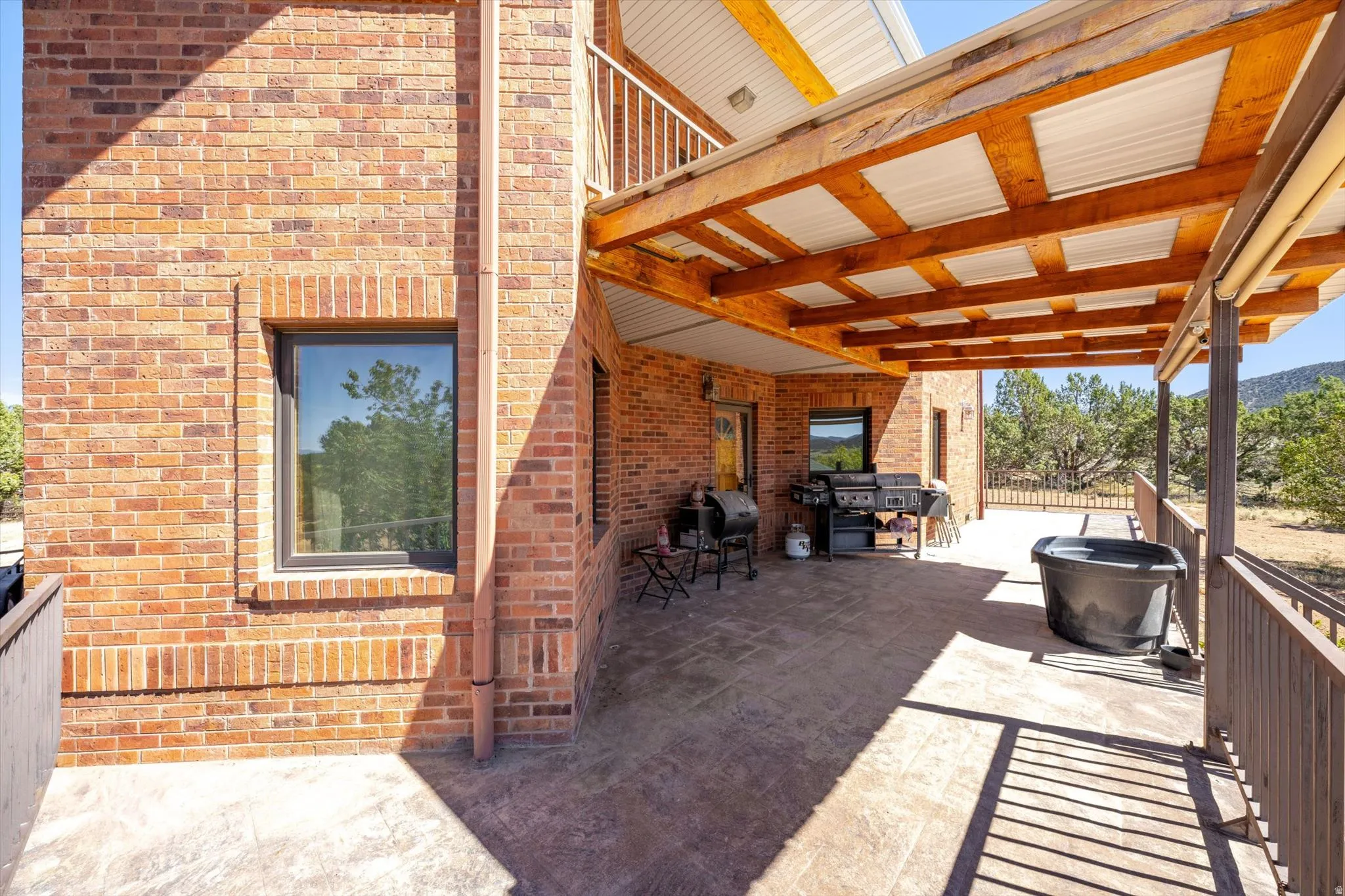 Brick exterior with a covered patio featuring exposed wood beams and a corrugated metal roof