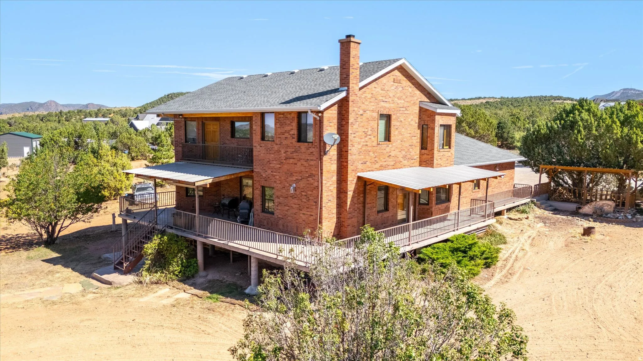 Brick exterior residence featuring multiple covered decks, an upper-level balcony, and a prominent chimney