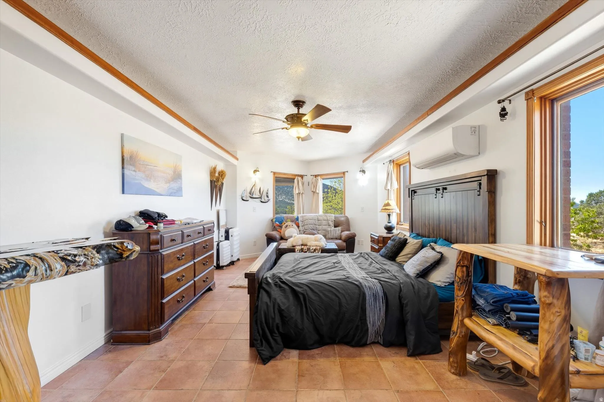 Terra cotta tile flooring, wood-trimmed windows, a ceiling fan, and a wall-mounted air conditioning unit