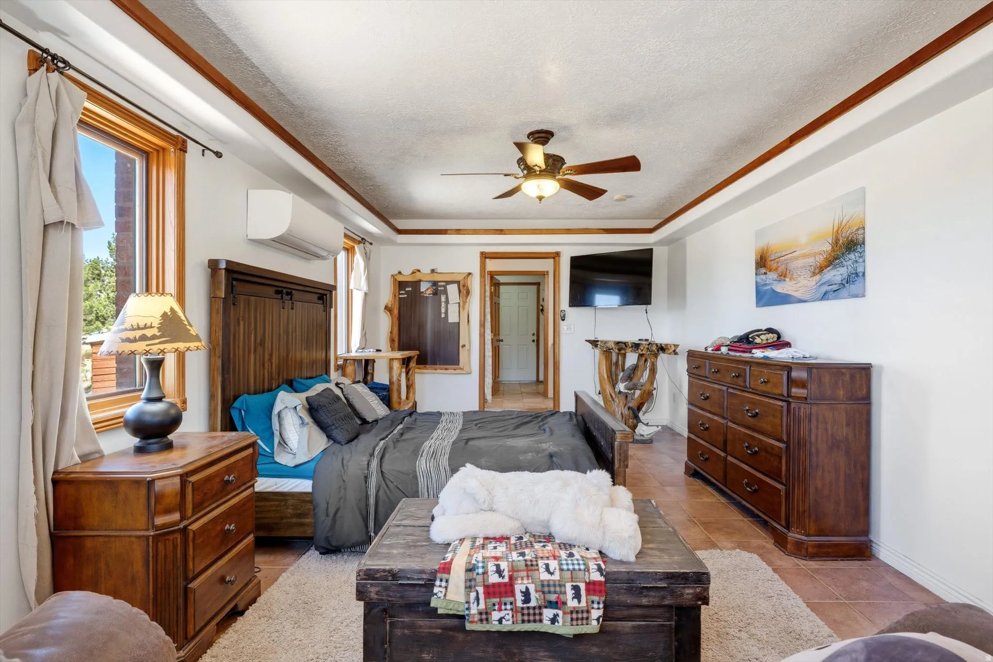 Wood-finish flooring, ceiling fan, natural wood trim, built-in air conditioning unit, and a window providing natural light