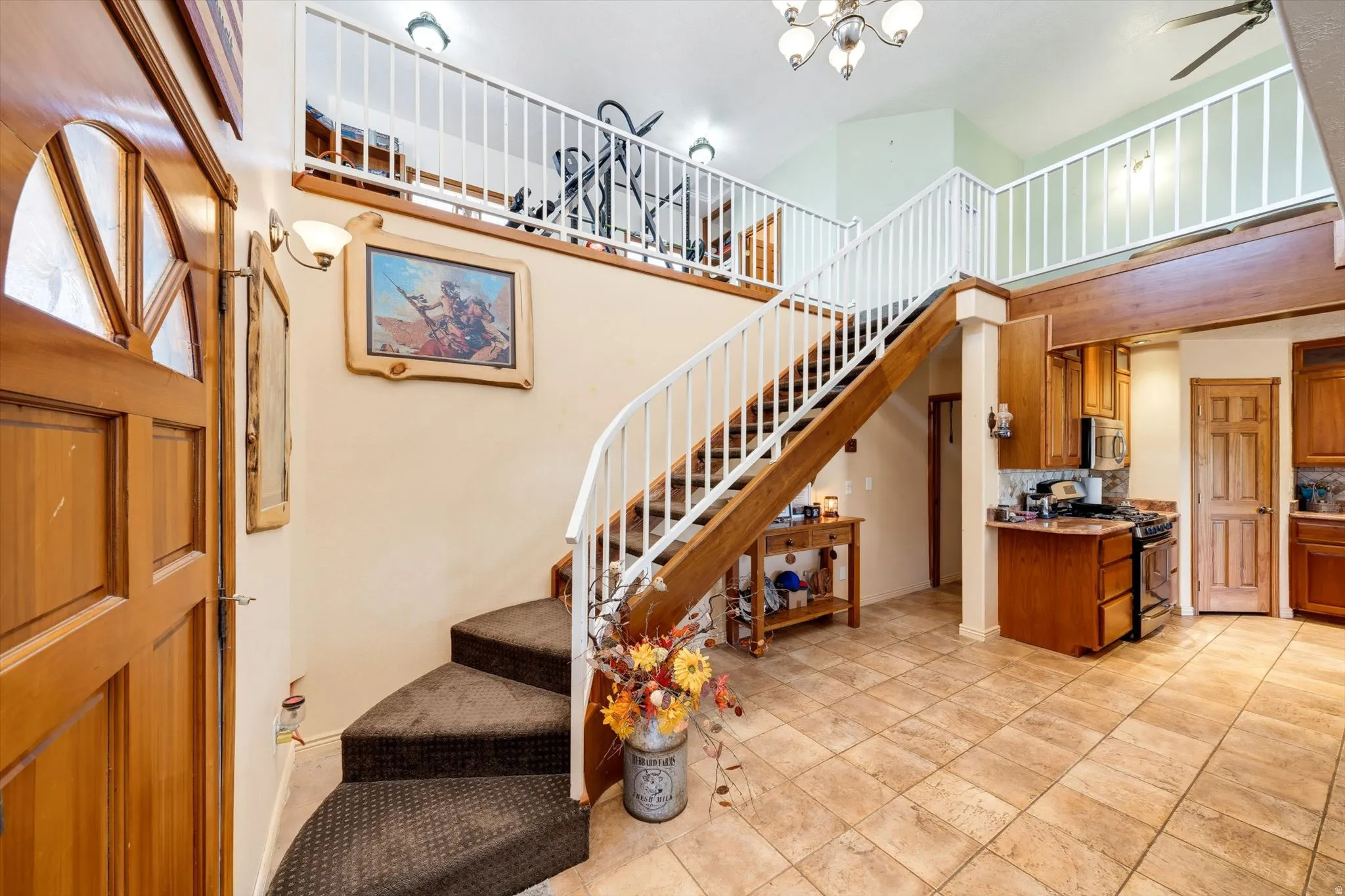 Open concept interior featuring a high vaulted ceiling, tile flooring, wood-finish cabinetry, and a full-height kitchen backsplash