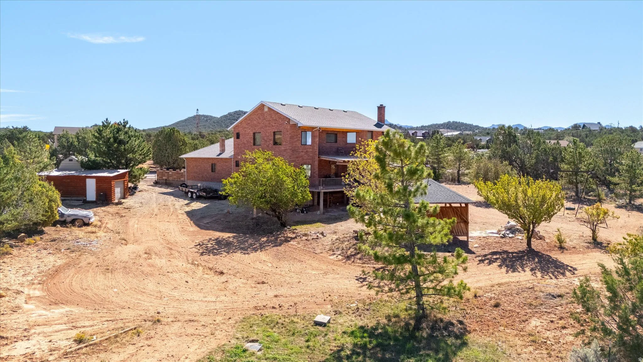 Brick exterior residence with multiple levels, an attached deck, and a detached outbuilding