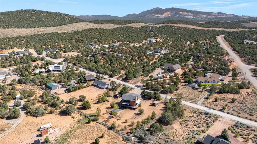 Expansive elevated property with surrounding natural terrain and distant mountainous backdrop