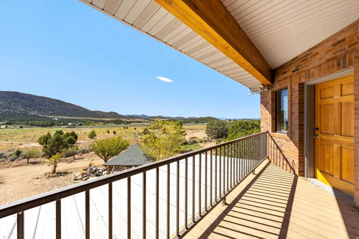 Expansive deck featuring wood-finish flooring, metal railing, and a brick exterior wall