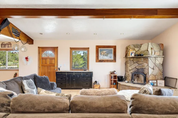 Stone-clad corner fireplace with a raised hearth, wood-paneled ceiling beams, recessed lighting, and tiled flooring