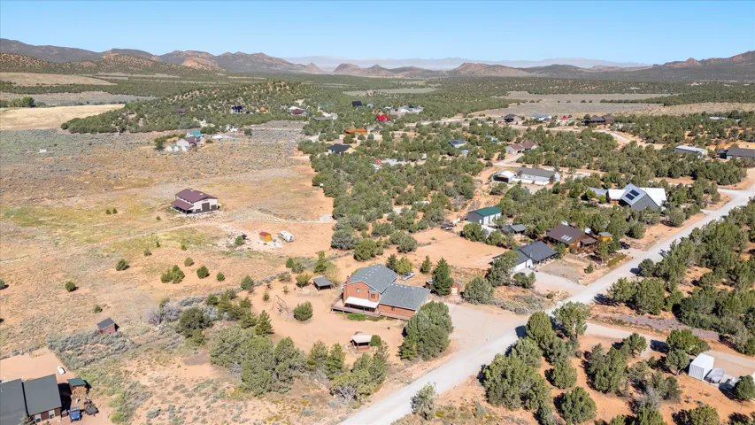 Expansive landscape featuring scattered residential properties, mature trees, and mountainous terrain