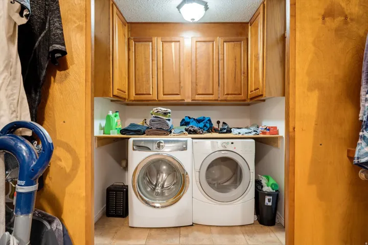 Laundry area featuring wood-finish cabinetry, a built-in shelf, and tile flooring