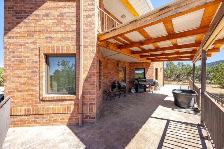 Brick exterior with a covered patio featuring exposed wood beams and a corrugated metal roof