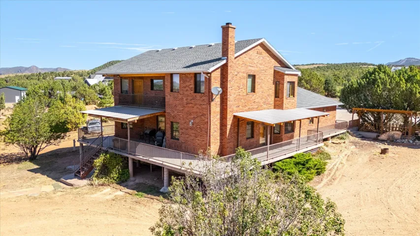 Brick exterior residence featuring multiple covered decks, an upper-level balcony, and a prominent chimney