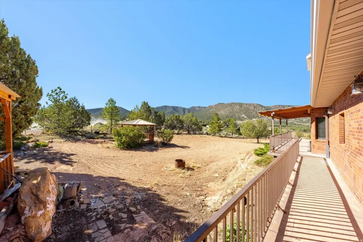 Expansive outdoor space featuring a brick exterior, covered patio, wood-framed gazebo, and mountain backdrop
