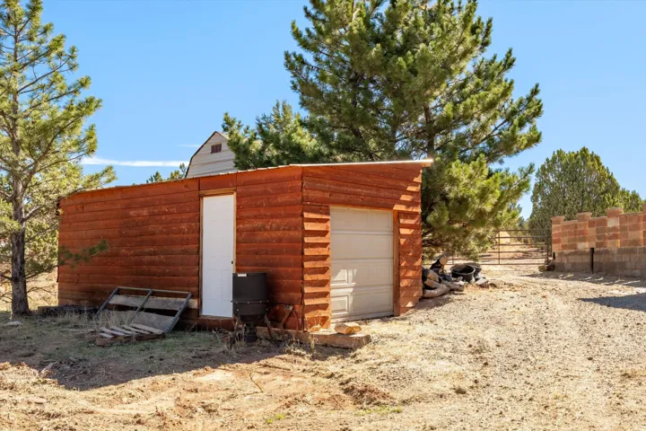 Detached utility building with horizontal wood siding, a single pedestrian door, and a garage door