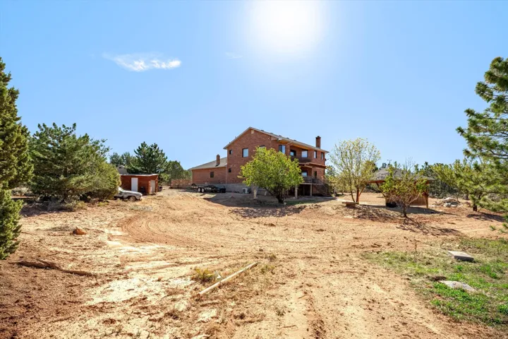 Expansive property featuring a brick exterior residence with multiple levels, an outdoor balcony, an detached shed, and a covered gazebo