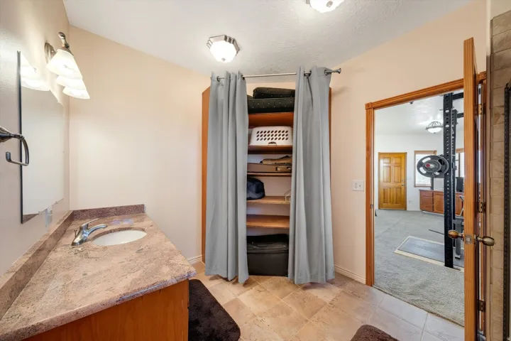Vanity with stone countertop, undermount sink, and chrome faucet