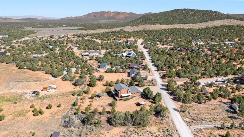 Expansive property with a dirt road, surrounding natural vegetation, and distant mountain backdrop