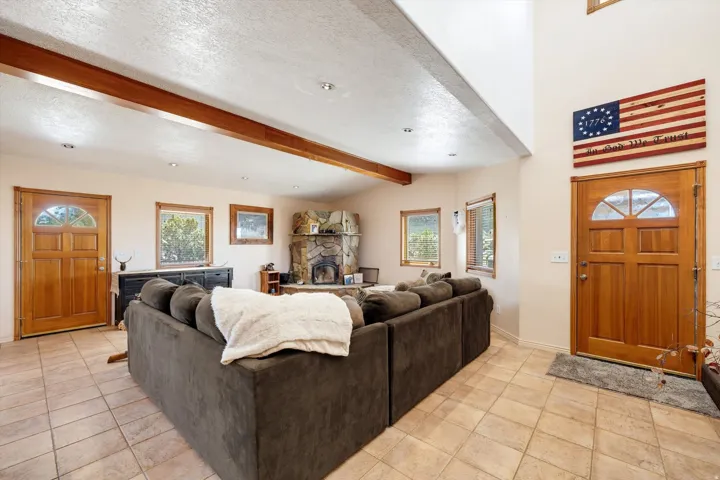 Ceramic tile flooring, exposed wood beam, recessed lighting, stone fireplace, and wood-framed windows