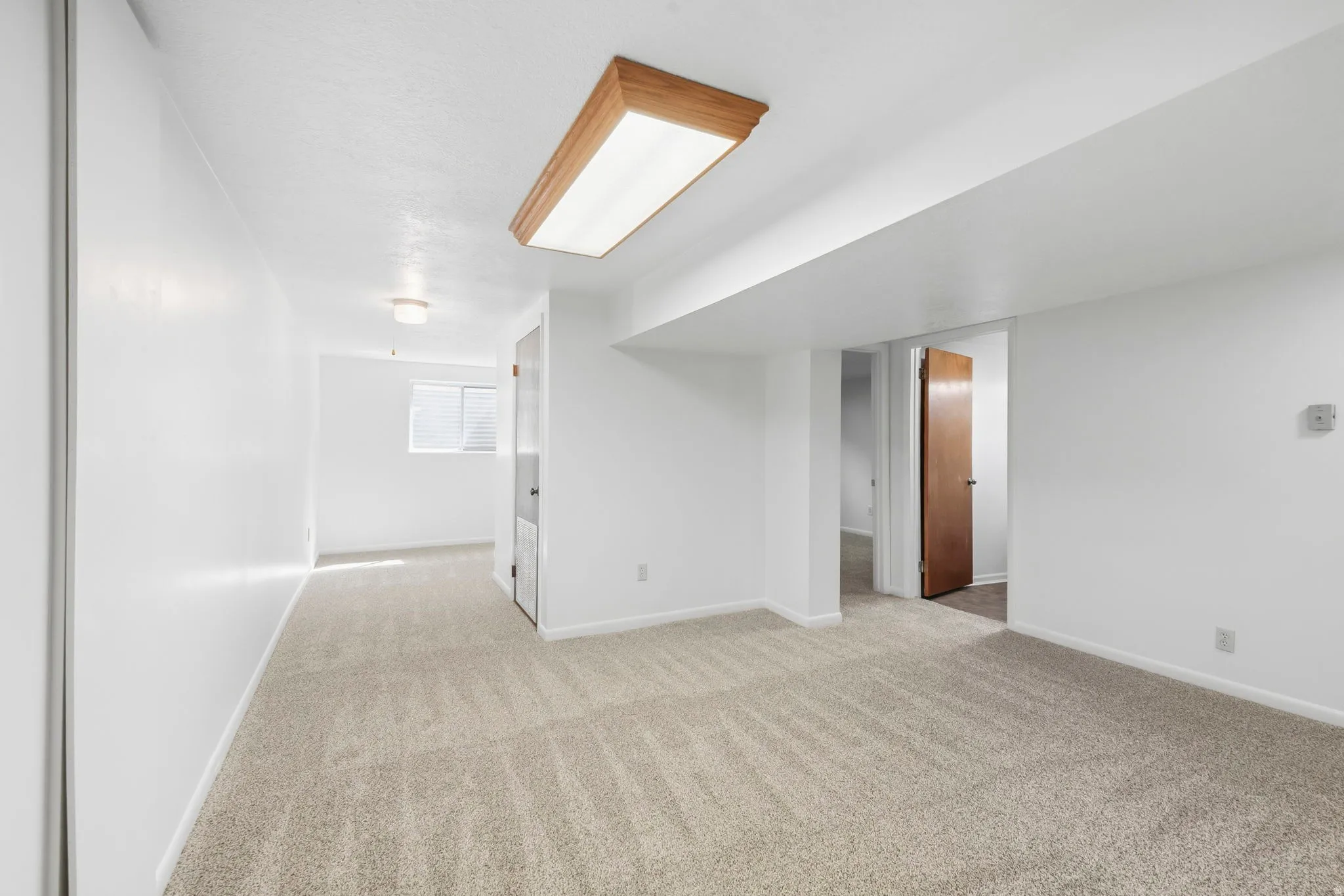 Neutral-toned carpeting, white walls, and a wood-framed ceiling light fixture