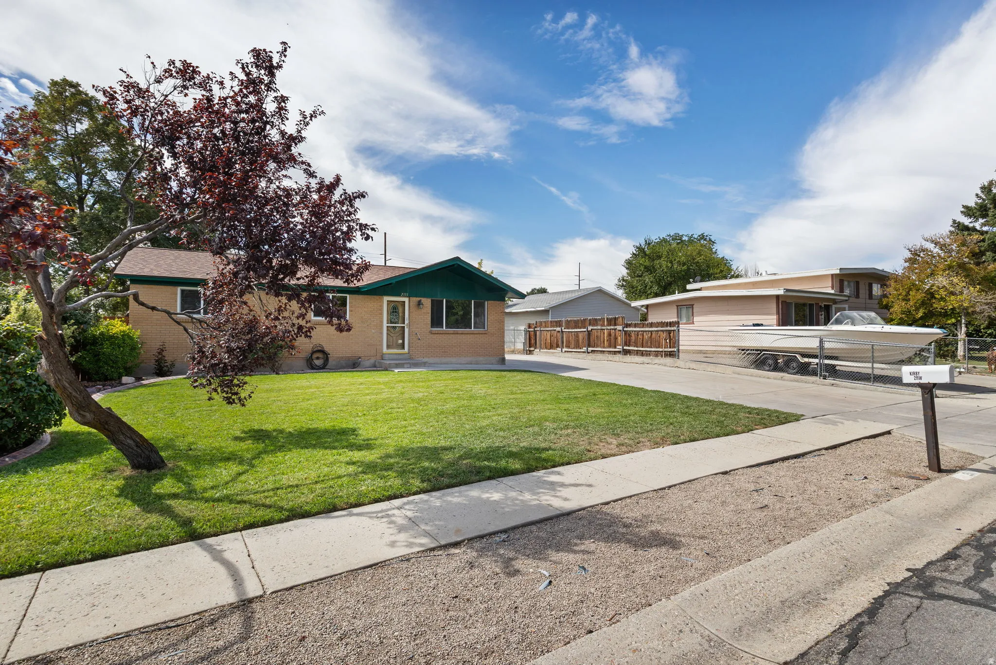 Brick exterior with green trim accents and a well-maintained lawn