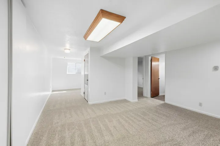 Neutral-toned carpeting, white walls, and a wood-framed ceiling light fixture