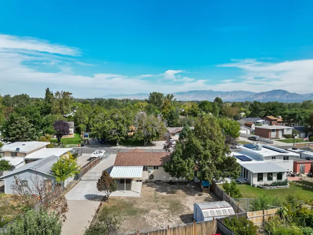 Single-story residence featuring a covered patio, a detached shed, a fenced perimeter, and a paved driveway