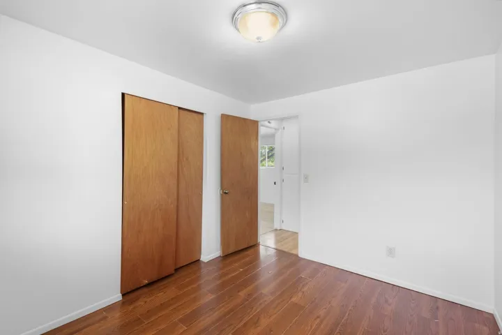 Wood-finish flooring, white painted walls, natural wood sliding closet doors, and recessed ceiling light fixture