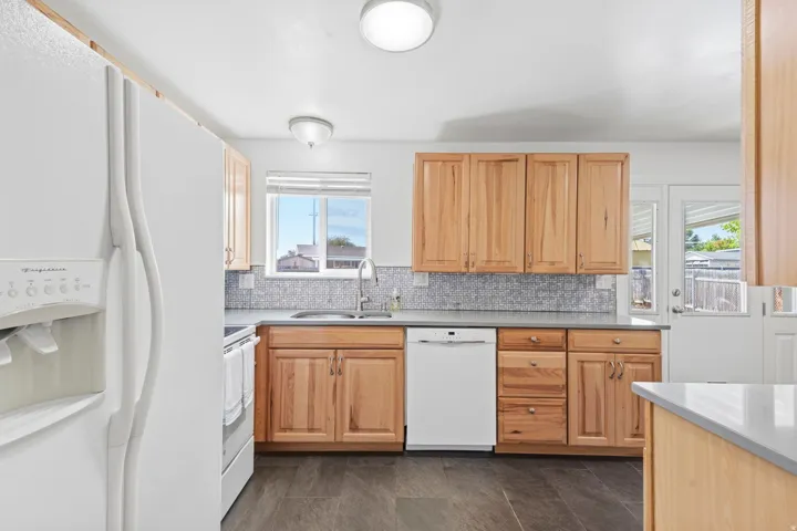 Kitchen featuring wood cabinetry, light-toned countertops, tile backsplash, and dark wood-finish flooring
