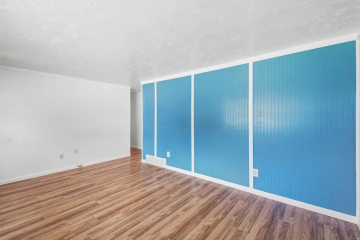 Wood-finish flooring throughout, bright white wall paint, and a textured ceiling